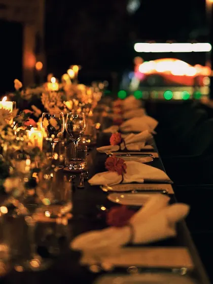 A long table set for an elegant dinner, with soft lighting and beautiful floral arrangements creating a cozy and sophisticated vibe.