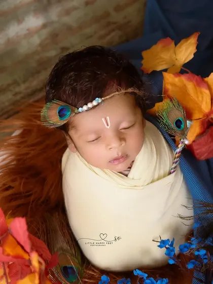 Wrapped in cream and surrounded by autumn leaves and peacock feathers, this little Kanha looks so peaceful. The combination of colors and textures creates a unique and artistic portrait.