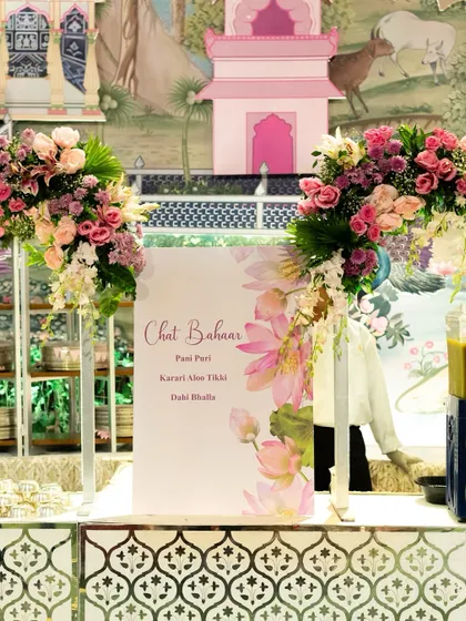 A "Chaat Bahaar" counter elegantly decorated with fresh flowers and a beautifully designed menu. This setup elevates a simple chaat station into a sophisticated culinary highlight.