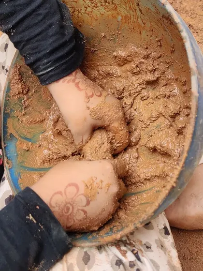 A close-up of hands mixing mud, a simple activity that provides immense sensory feedback and creative freedom.