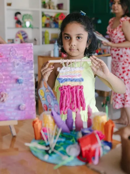 This camper proudly holds up the colorful tapestry she made. Our instructors guide kids through each step, making complex crafts like weaving accessible and fun for everyone.