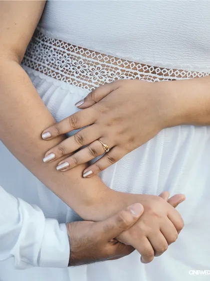 A close-up detail shot of a couple's hands during their pre-wedding shoot, showcasing the engagement ring and their gentle touch.