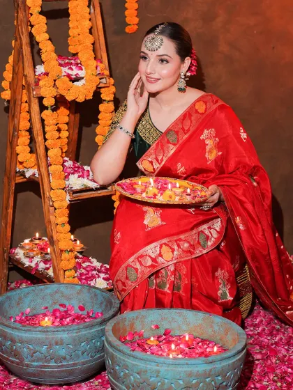 A full festive setup, with our model looking radiant in the red saree, holding a plate of diyas.