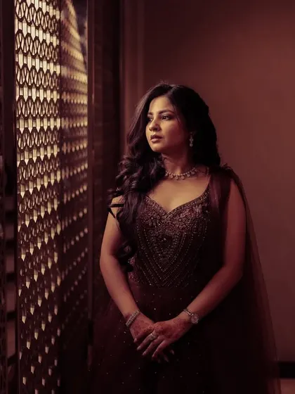A pensive portrait of a woman by a window, with beautiful light filtering through a jali screen.