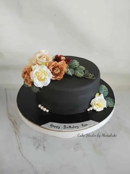 You can never go wrong with a classic black cake and flowers. This design is simple yet striking, with a spray of delicate flowers providing a beautiful contrast against the dark, smooth finish.
