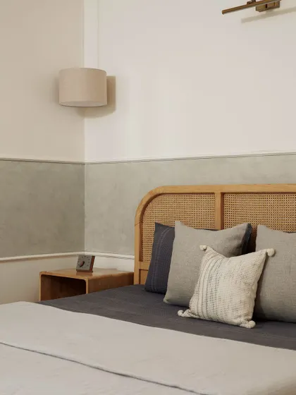 This bedroom embodies the essence of Japandi design, blending the simplicity of Japanese minimalism with Scandinavian warmth. The rattan headboard, textured lime-wash wall, and soft, neutral bedding come together to create a sanctuary of calm.