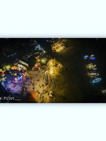 An overhead view of the bustling Assi Ghat in Varanasi at night, showing people and boats along the river Ganga.
