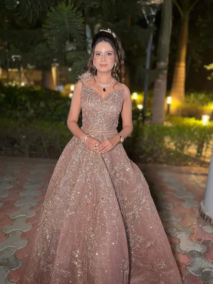 This bride is living her fairytale moment. Her shimmering gown is paired with a soft, glossy makeup look and a romantic half-up hairstyle, perfect for an engagement party.