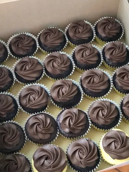 A box of classic chocolate cupcakes with a simple, elegant buttercream swirl.