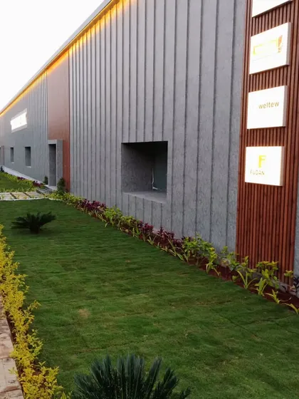 A long view of a commercial landscape, showing a neat strip of lawn bordered by colorful plants. This creates a clean, professional look along the building's facade.