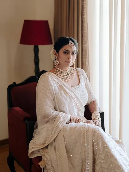 An elegant bridal portrait, with the bride seated in a classic armchair. The soft window light and her serene expression create a timeless and beautiful image.