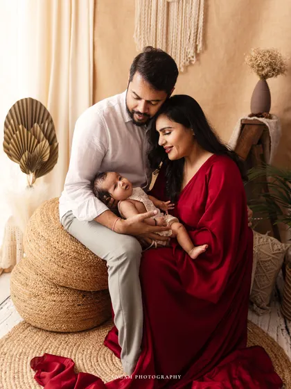 A new family shares a quiet moment in a boho-inspired setting. The parents gaze lovingly at their newborn, creating a serene and beautiful first family portrait.