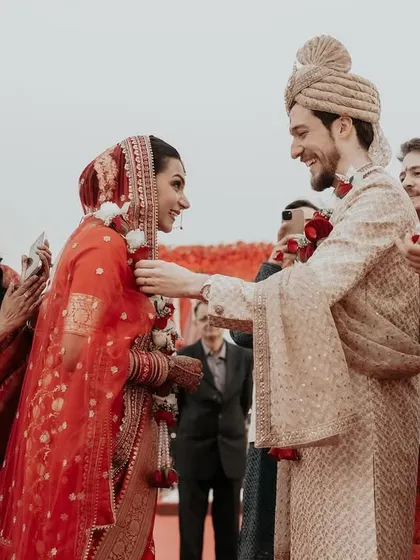 The varmala exchange. This shot captures the happy, smiling interaction between the bride and groom as they exchange garlands, surrounded by their families.