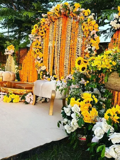 A lush Haldi seating area with a dense arch of marigolds, sunflowers, and white roses.