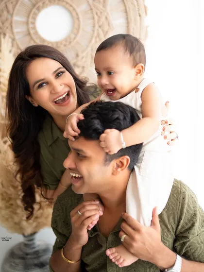 A candid family photo full of laughter and fun, with the baby getting a shoulder ride from dad.