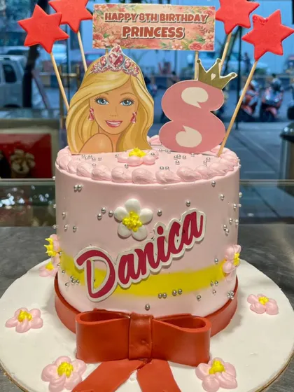 A pretty-in-pink Barbie cake for a princess's birthday. This design is personalized with the birthday girl's name and age, complete with a big red bow.