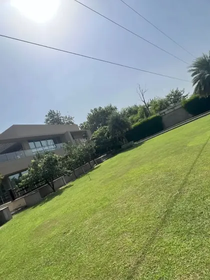 A view of a large residential property with a vast, sloping lawn. We have the expertise and equipment to install and maintain turf on challenging terrains.