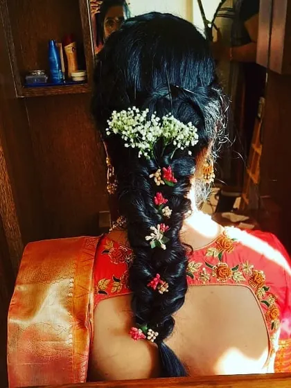 This is a beautiful fishtail braid, a popular choice for sangeet or mehendi functions. It's decorated with a mix of baby's breath and small colorful flowers for a fresh, bohemian vibe.