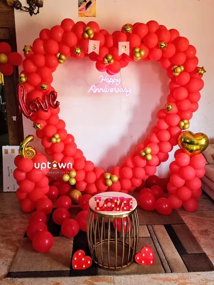 A romantic heart-shaped balloon arch for an anniversary celebration at home.