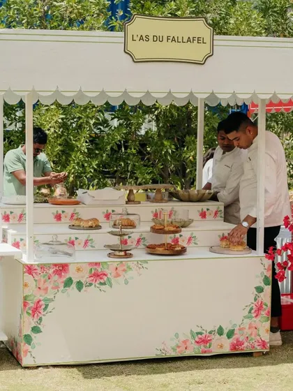 A beautiful falafel stall with a floral-printed facade, continuing the Parisian market theme and offering guests a delightful culinary experience.