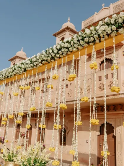 A beautiful curtain of hanging marigold and jasmine flowers creates a traditional and fragrant backdrop for a royal Haldi ceremony in Rajasthan.