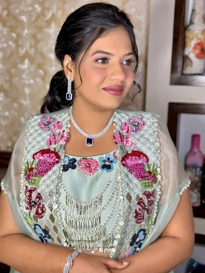A side profile showing the soft makeup and elegant hairstyle. This is a perfect look for any wedding guest who wants to look polished and chic.
