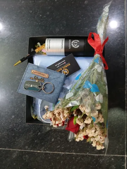 This gift hamper is packed with love, featuring a personalized denim wallet and keychain, a shirt, a pen, deodorant, and a lovely bouquet.