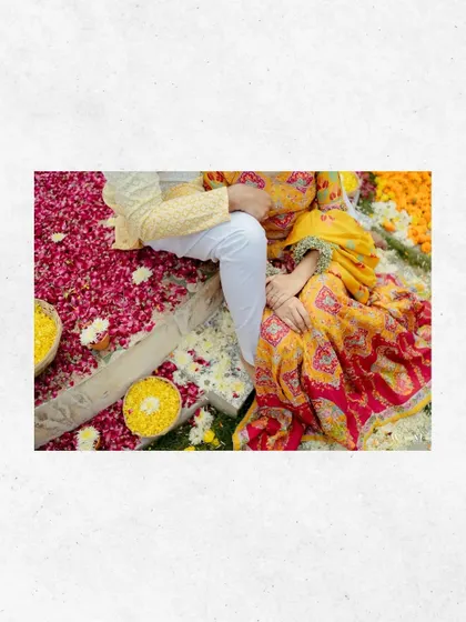 An intimate, artistic shot of the couple during their Haldi ceremony, surrounded by a bed of flowers. This photo focuses on their connection and the beautiful details of the ritual.