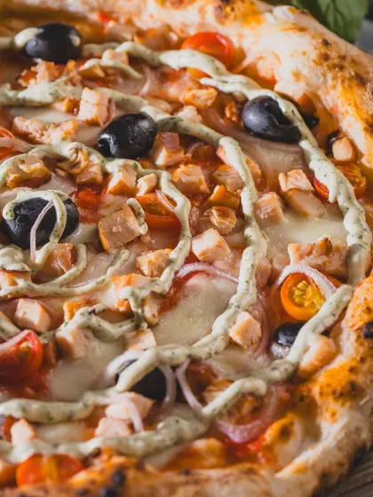 A close-up of the Smoked Chicken pizza, showing the creamy swirl and fresh toppings.