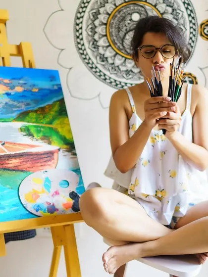 A moment of fun in my studio, sitting with a finished landscape painting and a yin-yang mandala mural in the background. Art for me is about both focus and freedom.