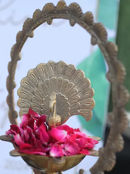 A close-up of a beautiful brass peacock lamp, filled with fresh rose petals. Small, traditional details like this add a touch of elegance and cultural richness to the welcome area.