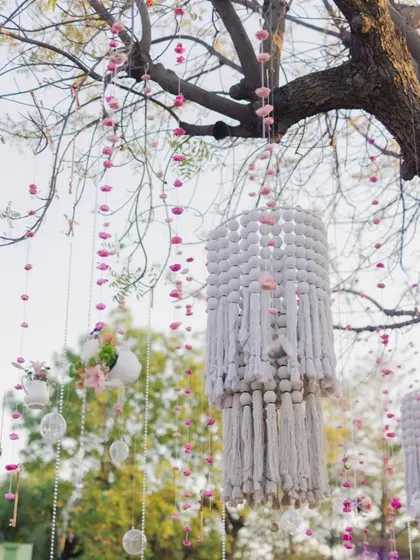 Intricate handmade macrame chandeliers and floral hangings adorn the trees, adding a bohemian and crafty touch to the whimsical decor.