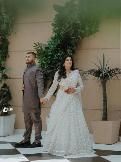A stylish portrait of Gaurav and Mansi holding hands, showcasing their elegant, coordinated outfits.