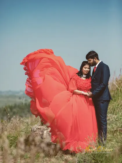 A dramatic pre-wedding photo with the bride's vibrant red dress flowing in the wind. This creates a powerful and memorable image.