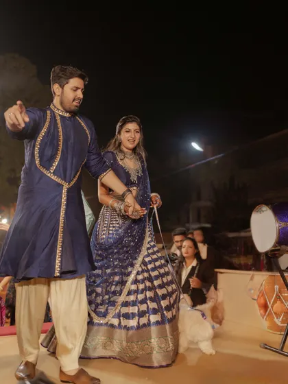 A Timeless Garba Night: The couple's coordinated Pichwai-inspired outfits in deep blue, a classic and elegant choice for a traditional Gujarati garba.