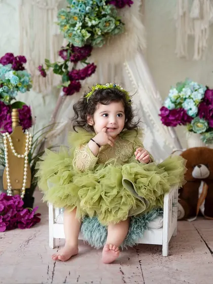 A curious little girl in a beautiful green dress. The boho-inspired setup with pearls and teddy bears creates a stylish and sweet portrait.