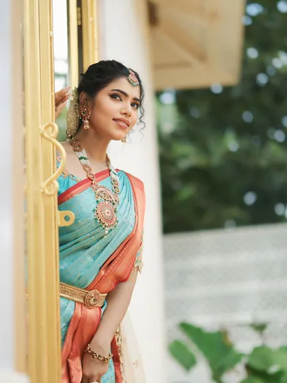 A lovely window shot that highlights the soft, glowing makeup and the intricate details of the jewelry.