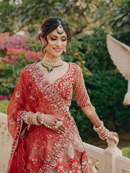 A beautiful candid shot of the bride in a garden setting. The makeup looks fresh and natural against the lush background.