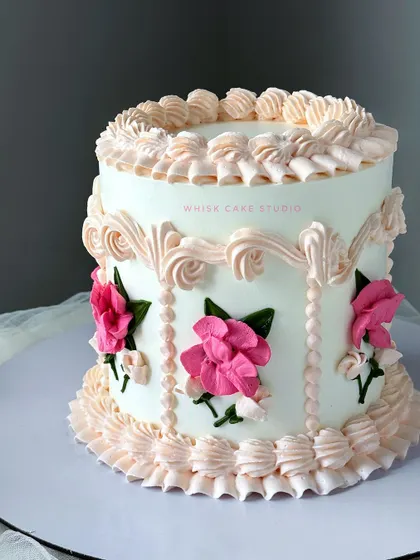 A vintage cake designed to turn heads. This single-tier cake features intricate Lambeth-style piping and delicate, hand-painted floral details.