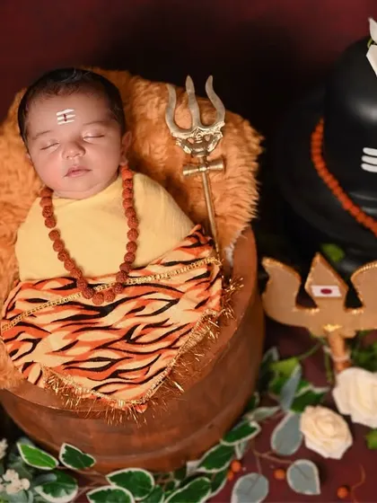 This newborn is styled as a peaceful Bala Shiva, sleeping soundly in a rustic pot. I use traditional elements like rudraksha beads and a small trishul to make the theme authentic and divine.