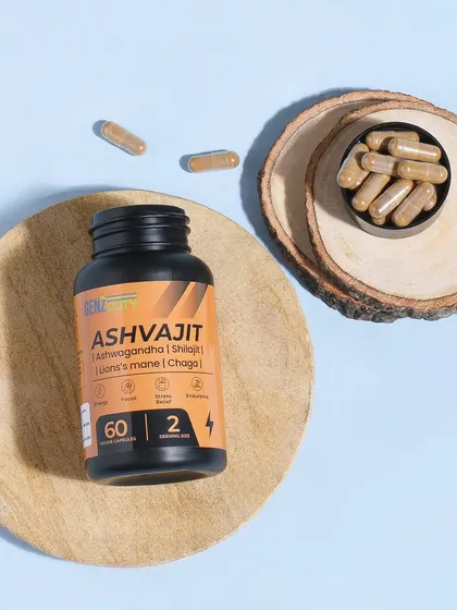 A clean, top down flatlay of an Ashwagandha supplement bottle on wooden surfaces. The blue background provides a nice contrast, and the scattered capsules show the product itself.