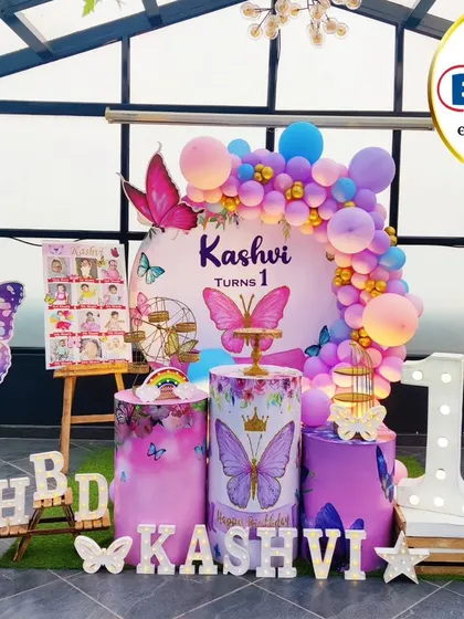 A stunning butterfly-themed first birthday on a rooftop. This outdoor setup features a beautiful balloon arch, large butterfly props, and a 'ONE' marquee table.