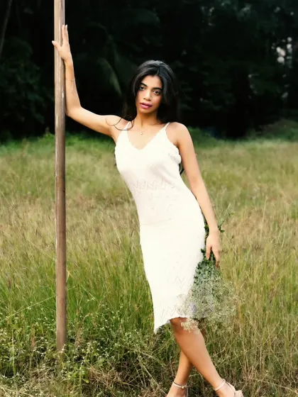 A classic, elegant pose against a wooden pole, with the lush green field stretching out behind.