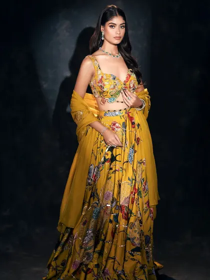 A vibrant and joyful full-length shot of a yellow floral lehenga. The dark background makes the colors pop, creating a captivating image for any collection.