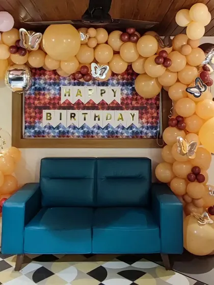 A simple and elegant organic balloon garland in pastel orange and silver. This half-arch frames a seating area and is accented with butterfly cutouts, perfect for a subtle and stylish celebration.