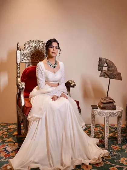Seated like royalty in a stunning all-white lehenga. This look is perfect for a sophisticated welcome dinner or a themed white party.