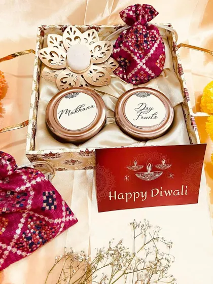 A beautiful Diwali gift set with a patterned box, two jars, a diya, and traditional potlis.