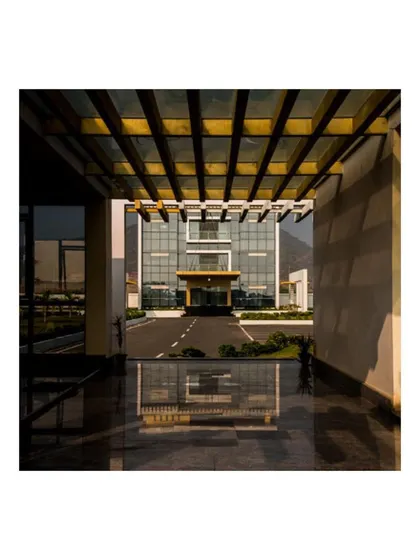 The entrance sequence at the Krishna Sai Granites campus is carefully choreographed. This image, taken from the walkway, shows how the path directs the eye toward the contemporary, glass-clad admin building, establishing it as the focal point.