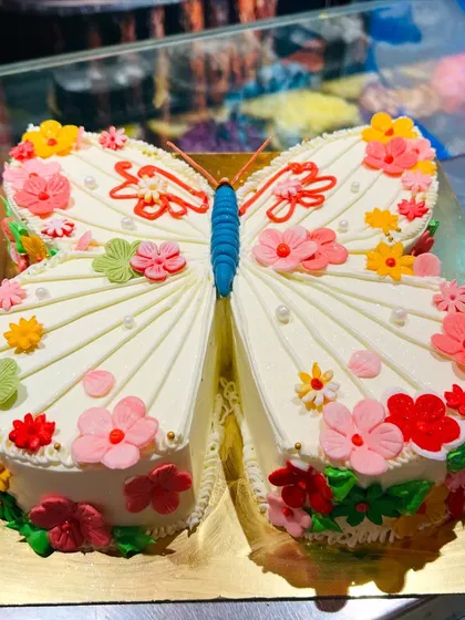 A unique cake sculpted into the shape of a butterfly, with wings decorated with colorful flowers.