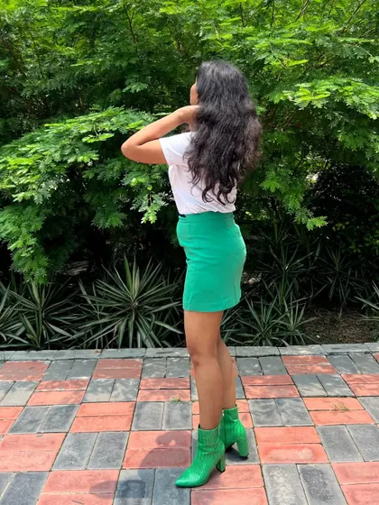 A side profile of the green-on-green outfit. The fitted skirt and heeled boots create a chic silhouette that's perfect for a day-to-night transition.